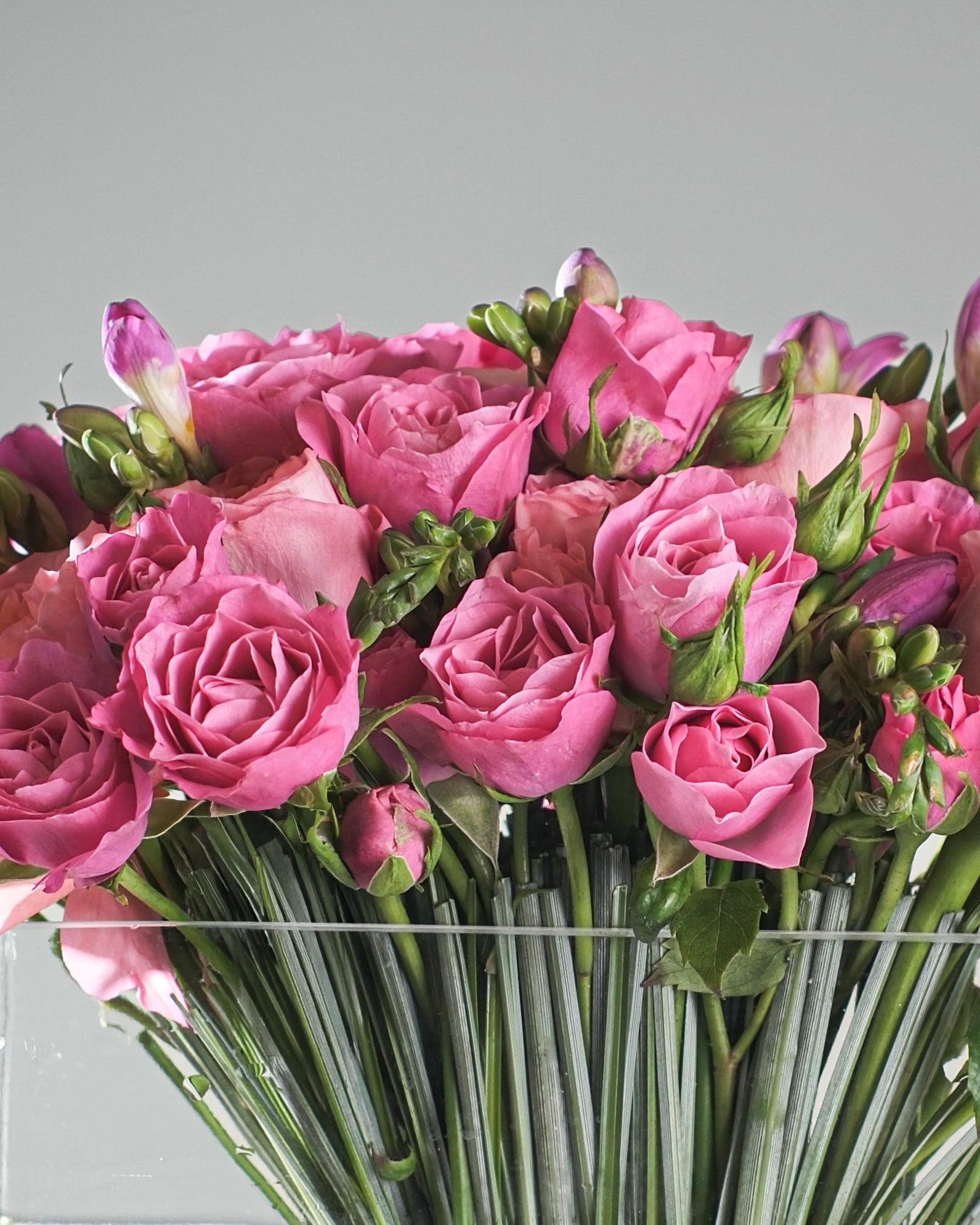 pink vase flower arrangement with garden roses, spray roses, freesia and bear grass by Casa Dei Fiori in Beverly Hills